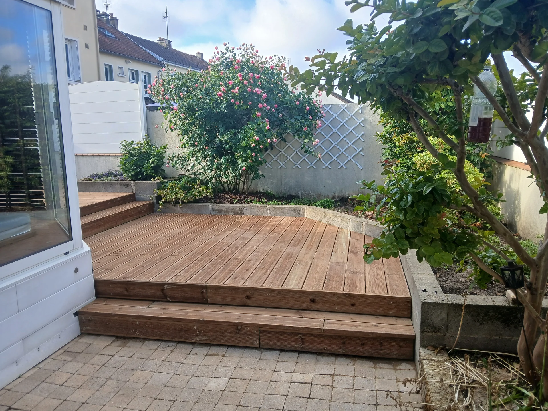 Terrasse en bois avec marches et rosiers dans un jardin