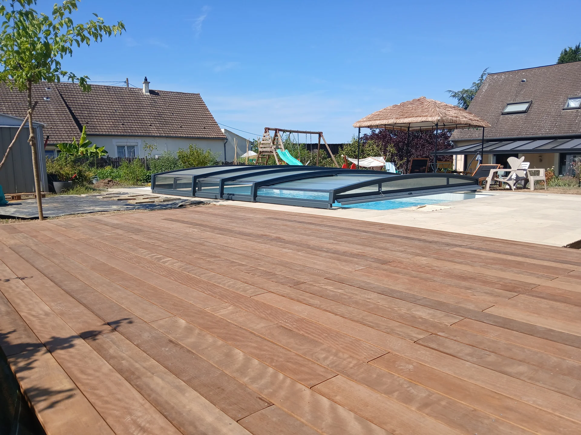 Terrasse en bois autour d’une piscine dans un jardin